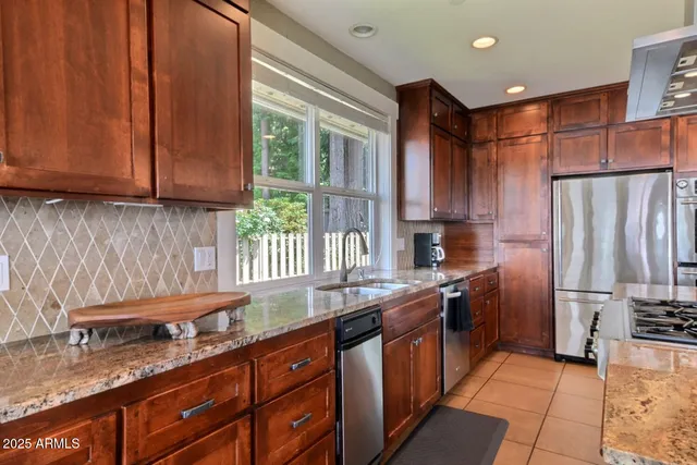 a kitchen with granite countertop a sink stainless steel appliances and cabinets