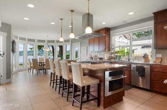 a kitchen with stainless steel appliances granite countertop table chairs stove and cabinets