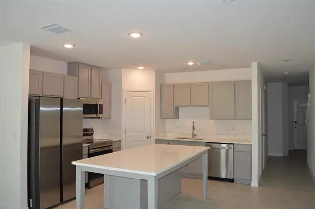 a kitchen with kitchen island a sink stainless steel appliances and refrigerator