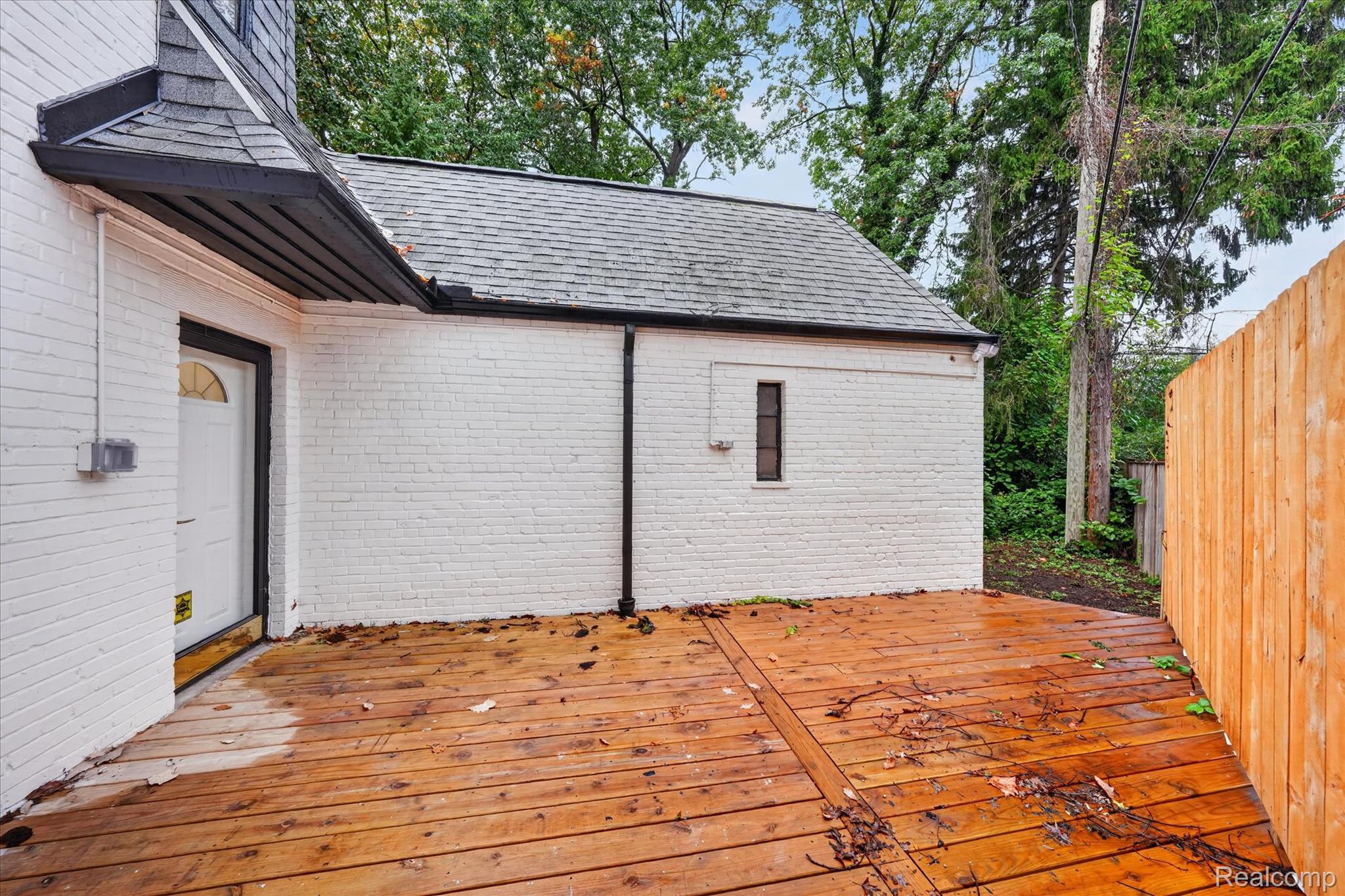 3250 Sherbourne Road Detroit, MI 48221 - Photo 33 of 36 Expansive wood-finish decking with a privacy fence, complemented by a white brick exterior and a dark shingle roof