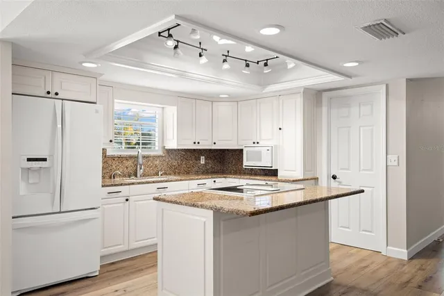 a large kitchen with kitchen island a large counter space a sink appliances and cabinets