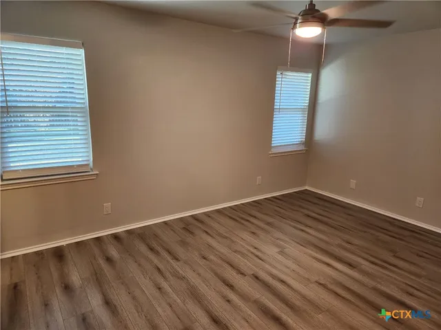 a view of an empty room with wooden floor and a window