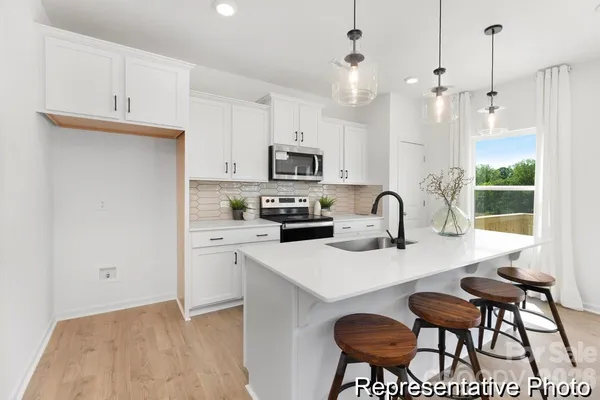 a kitchen with stainless steel appliances granite countertop a stove a sink a microwave a dining table and chairs with wooden floor