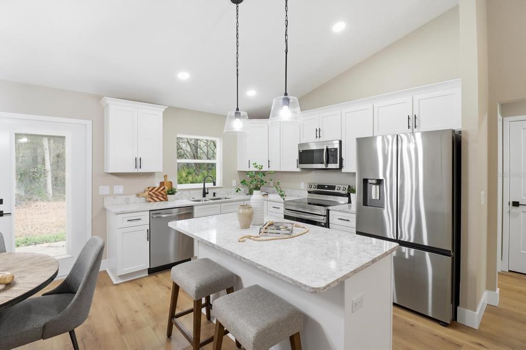 3671 East Ryan Street Inverness, FL 34453 - Photo 13 of 48 a kitchen with refrigerator a sink and chairs