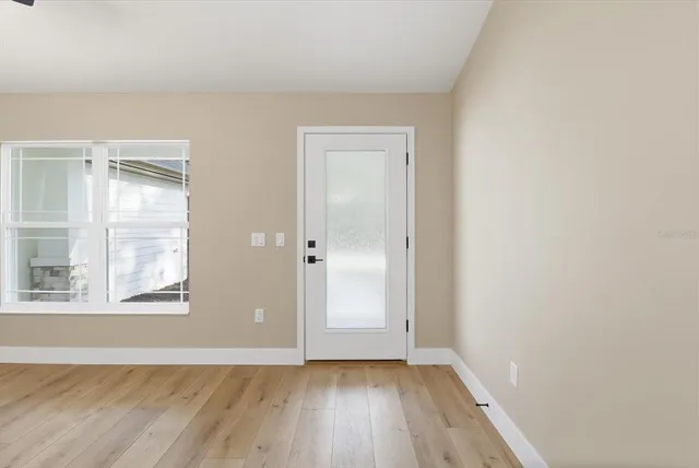 an empty room with wooden floor and windows