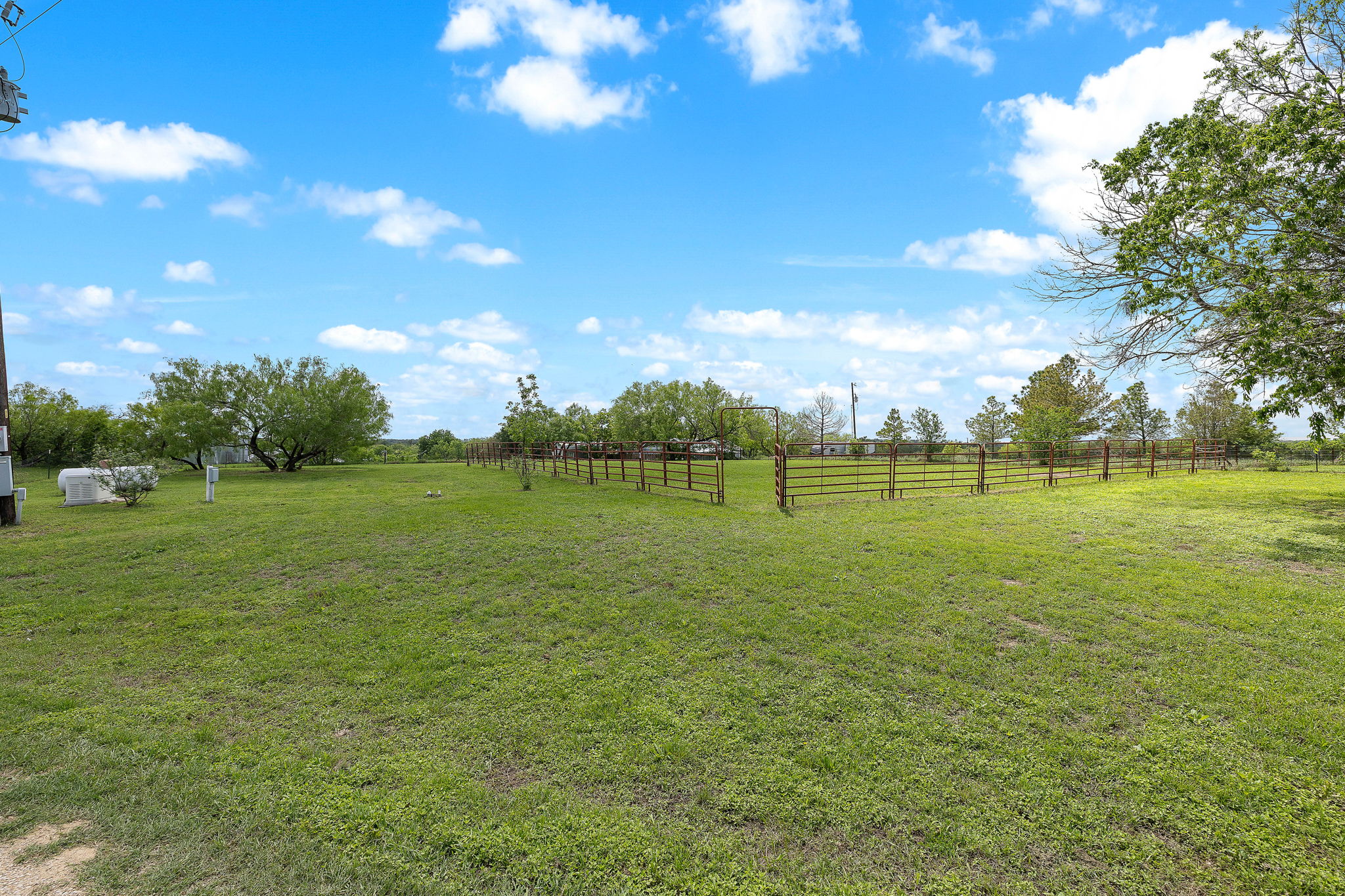571 Balch Road Elgin, TX 78621 - Photo 30 of 33 Expansive green space featuring perimeter fencing, mature trees, and a clear sky
