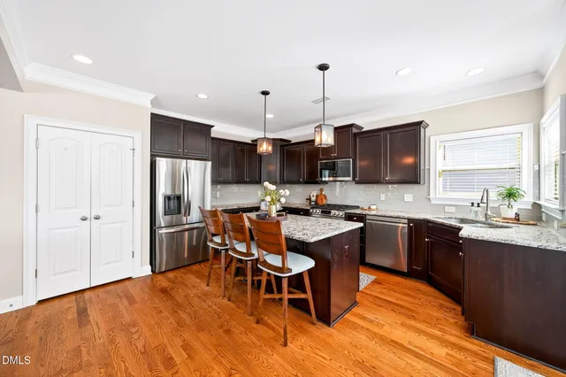 a kitchen with granite countertop kitchen island stainless steel appliances a sink stove and wooden floor