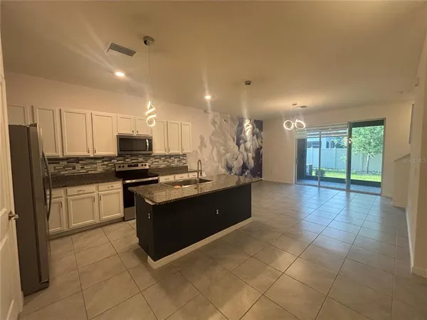 a large kitchen with stainless steel appliances granite countertop a stove and a refrigerator