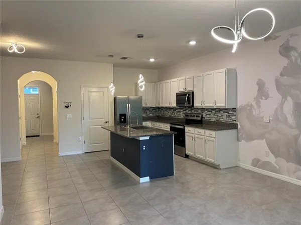 a large kitchen with kitchen island granite countertop a stove a sink a window and white cabinets