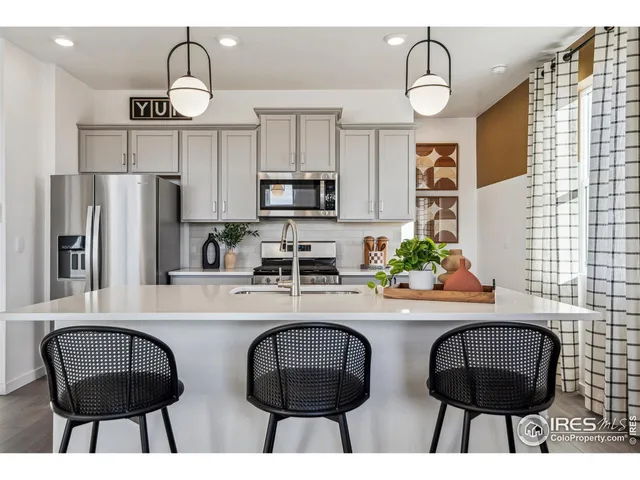 a kitchen with stainless steel appliances a dining table chairs and a refrigerator