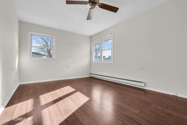a view of an empty room with a window and wooden floor