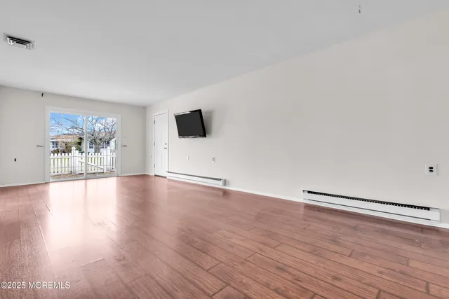 a view of a livingroom with wooden floor and a flat screen tv