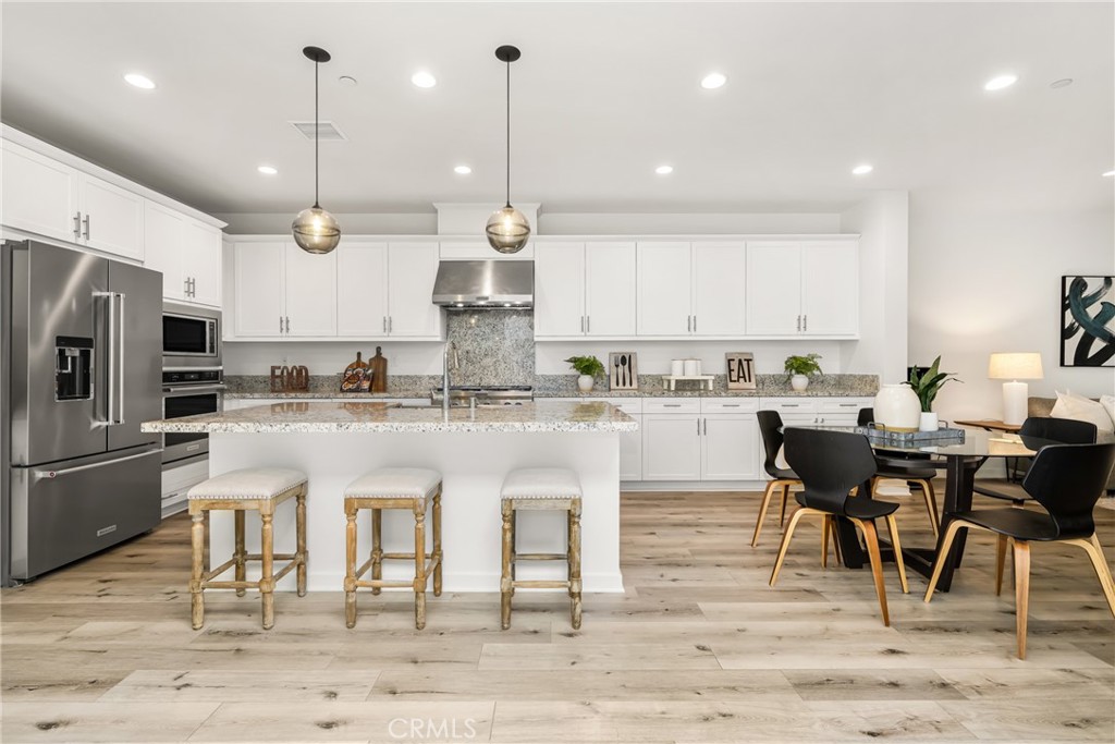 186 Terrapin Irvine, CA 92618 - Photo 8 of 39 a kitchen with stainless steel appliances kitchen island granite countertop a table chairs refrigerator and microwave