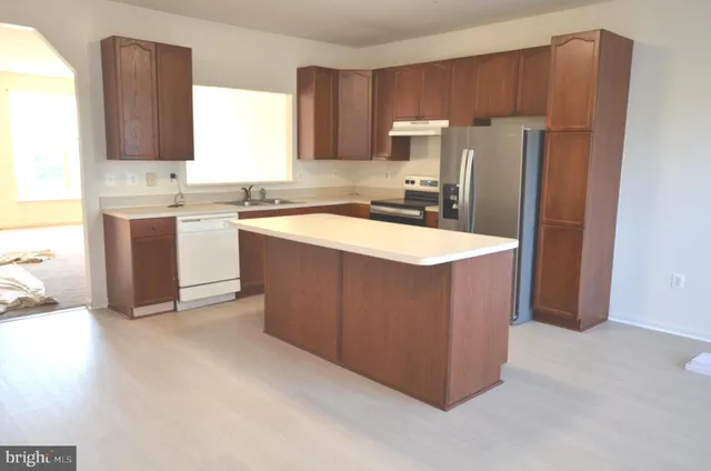 a kitchen with stainless steel appliances granite countertop a refrigerator a stove a sink and a microwave