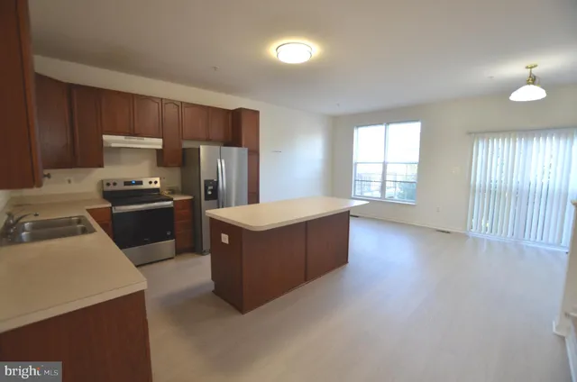 a kitchen with granite countertop a refrigerator a sink a stove and dishwasher