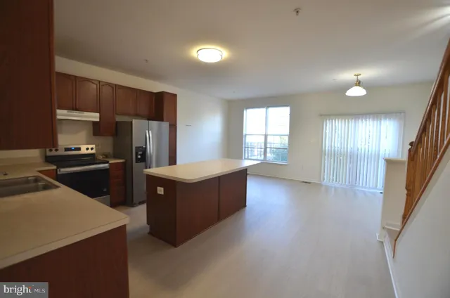 a kitchen with stainless steel appliances kitchen island granite countertop a refrigerator a sink dishwasher and a stove