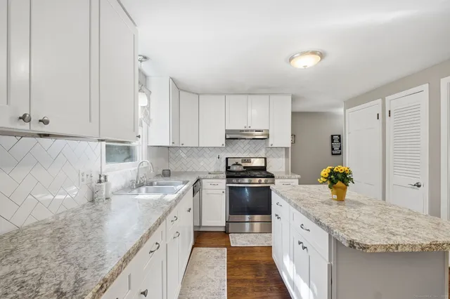 a kitchen with stainless steel appliances granite countertop a sink stove and cabinets