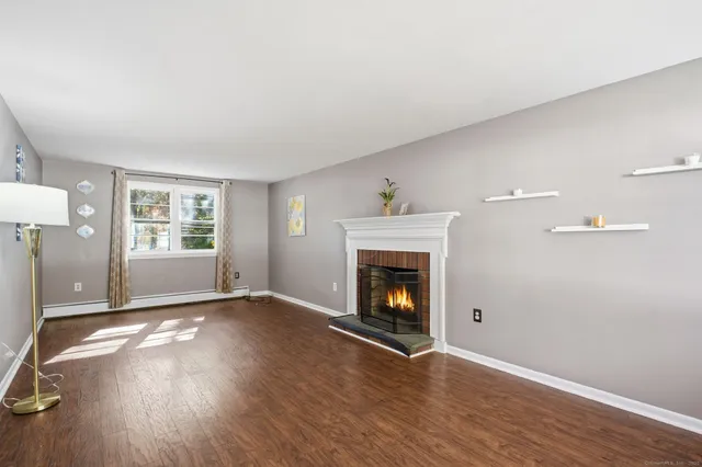 a view of empty room with wooden floor and fireplace