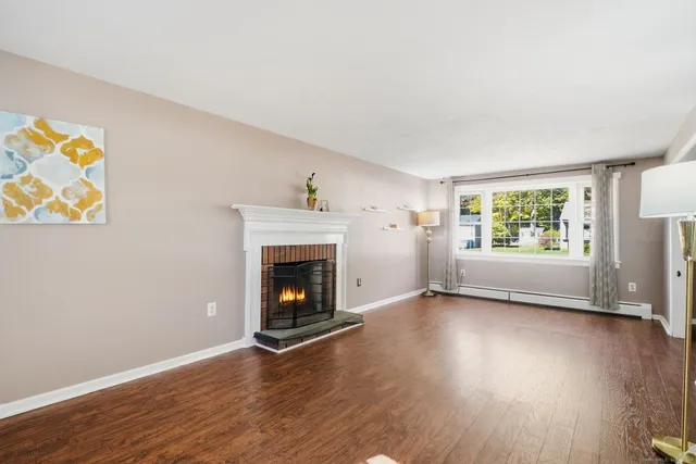 an empty room with windows fireplace and wooden floor