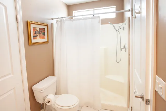 a white toilet sitting next to a shower