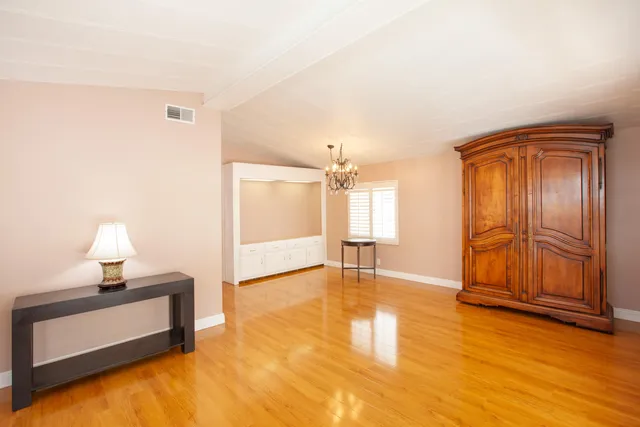 a view of an empty room and window with wooden floor