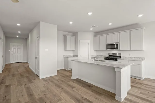 a large white kitchen with kitchen island a sink a stove a refrigerator and white cabinets