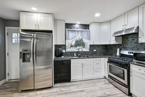 a kitchen with stainless steel appliances granite countertop a stove a refrigerator and a sink