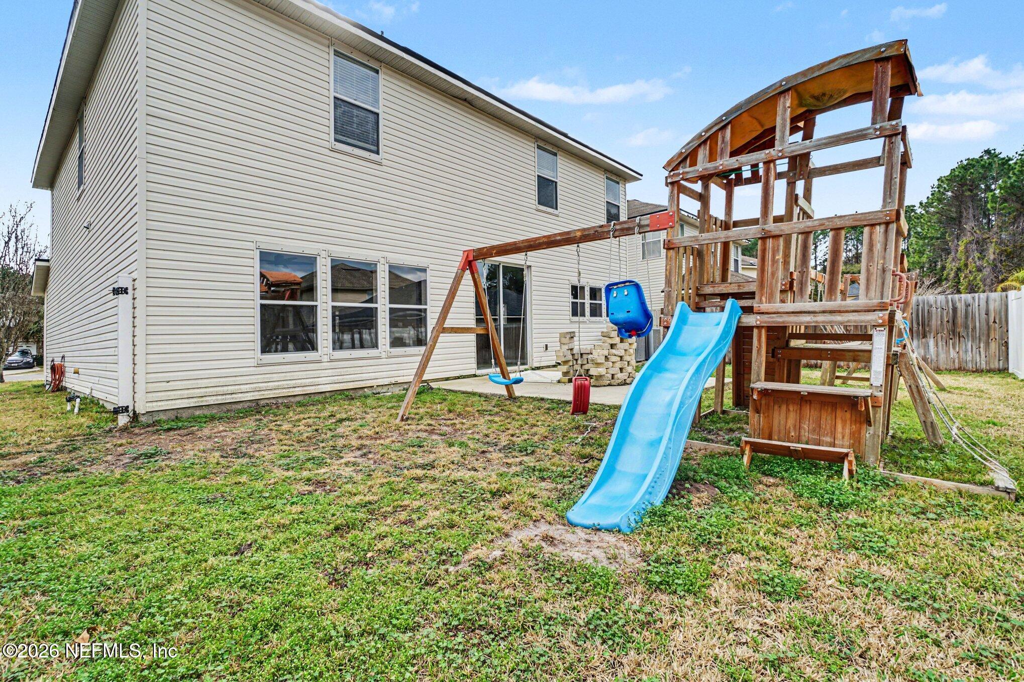 96039 Morton Lane Yulee, FL 32097 - Photo 26 of 27 a backyard of a house with childrens swings and slides