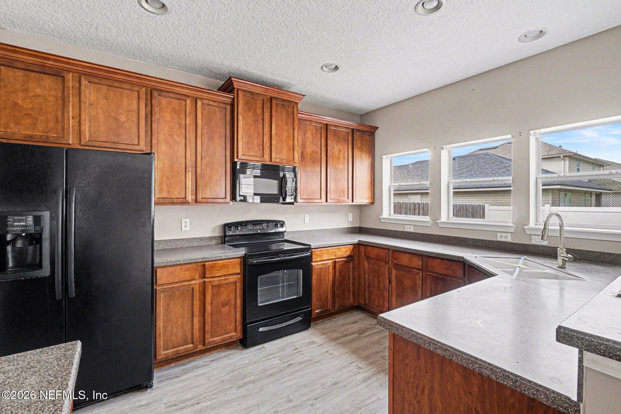 96039 Morton Lane Yulee, FL 32097 - Photo 9 of 27 a kitchen with stainless steel appliances granite countertop a stove a sink dishwasher a refrigerator and a microwave oven with wooden cabinets