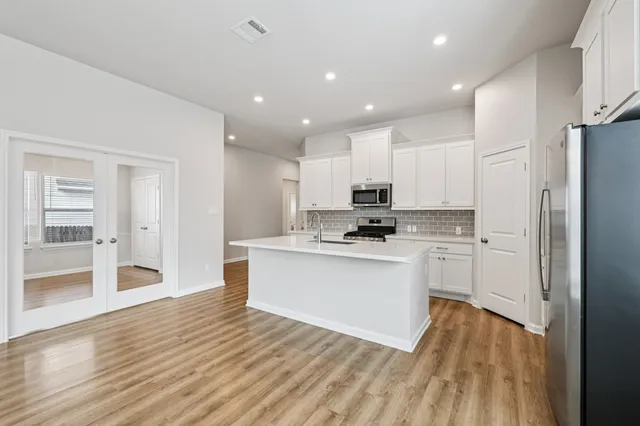 a large kitchen with stainless steel appliances a large counter top a stove and a refrigerator