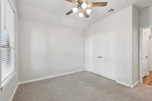 an empty room with a window and a fan