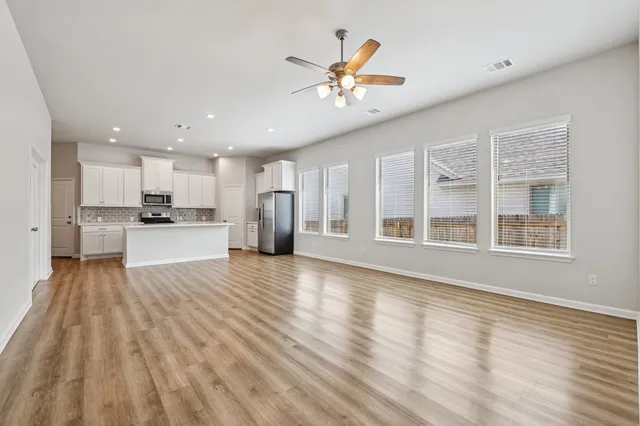 a view of an empty room with window and wooden floor