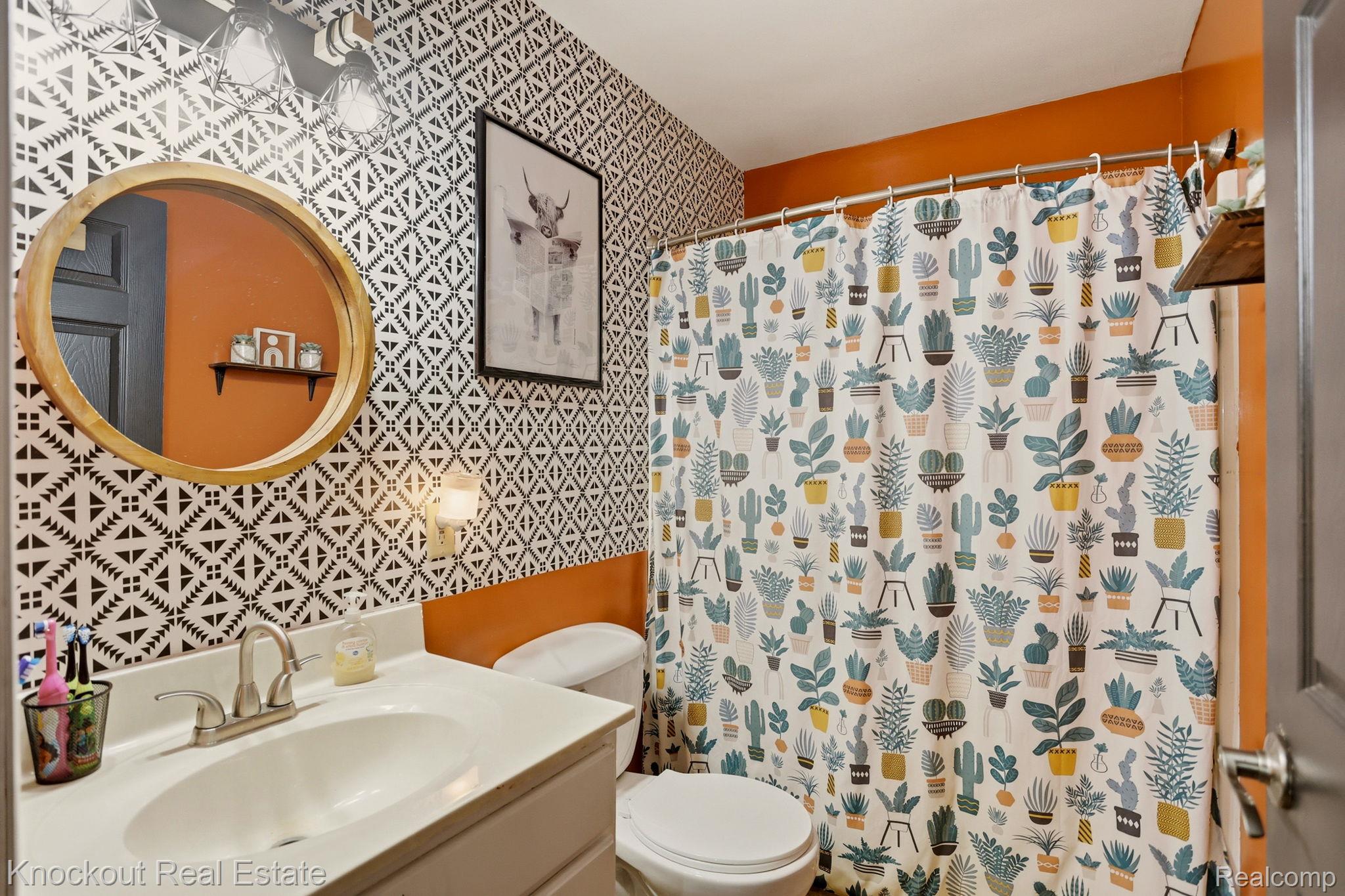 8845 Ormes Road Vassar, MI 48768 - Photo 26 of 35 Bathroom featuring a white vanity with an integrated sink, a wooden-framed round mirror, and a wall-mounted light fixture above