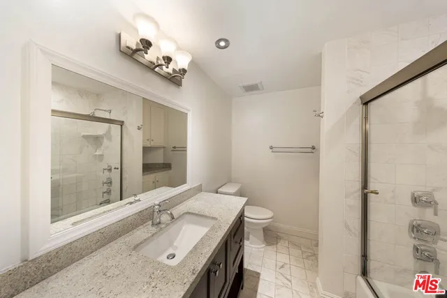 a bathroom with a granite countertop sink a toilet and shower