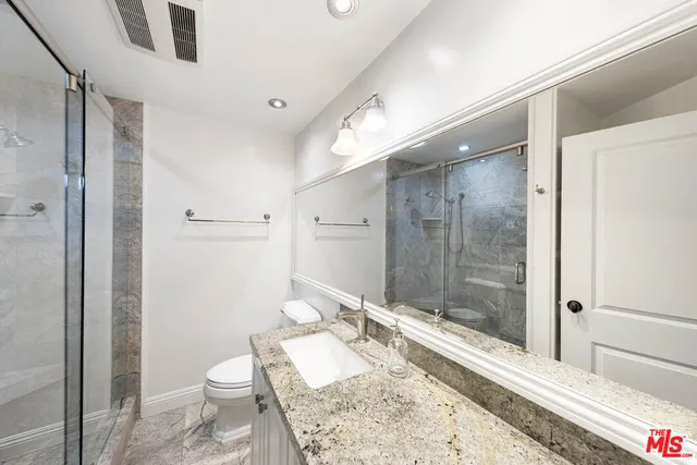 a bathroom with a granite countertop sink toilet and shower