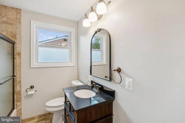 a bathroom with a granite countertop sink mirror and toilet