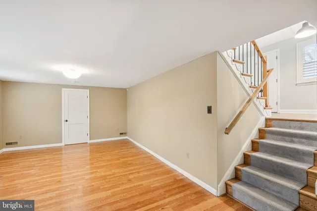 a view of an empty room with wooden floor and stairs