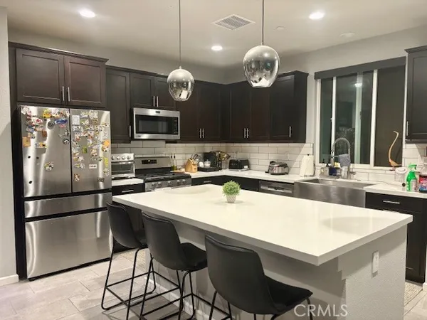 a kitchen with a refrigerator a sink and chairs