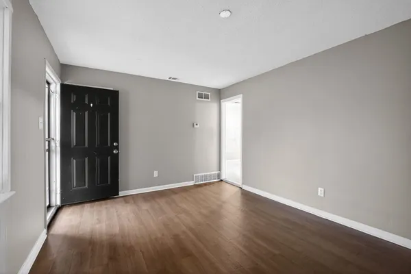 a view of an empty room with wooden floor and a window