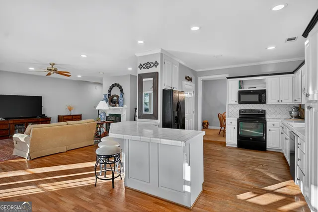 a living room with furniture a flat screen tv and kitchen view