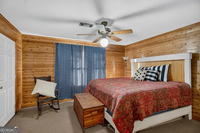 a bedroom with a bed a chair and a large window