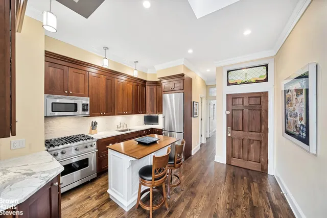 a kitchen with stainless steel appliances a refrigerator a stove a sink dishwasher and wooden cabinets with wooden floor