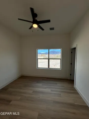 an empty room with wooden floor fan and windows