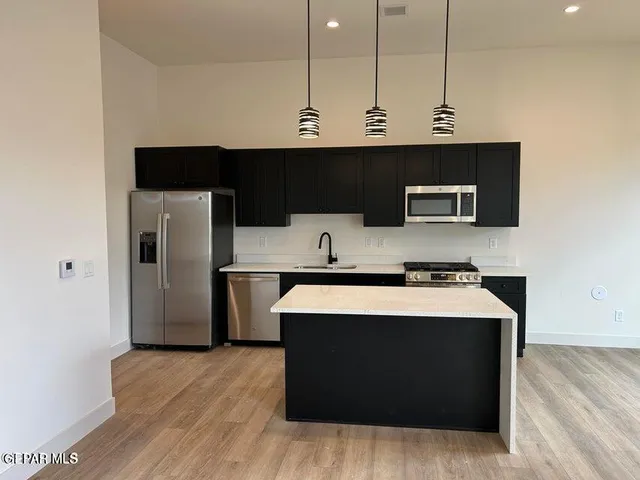 a kitchen with stainless steel appliances a stove a microwave a sink and a refrigerator