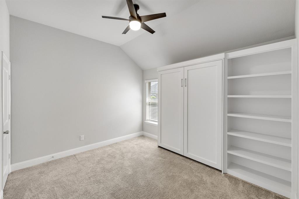 915 Timber Ridge Drive Justin, TX 76247 - Photo 27 of 39 Room featuring vaulted ceilings, a ceiling fan, plush carpeting, a built-in wall bed, and an integrated shelving unit