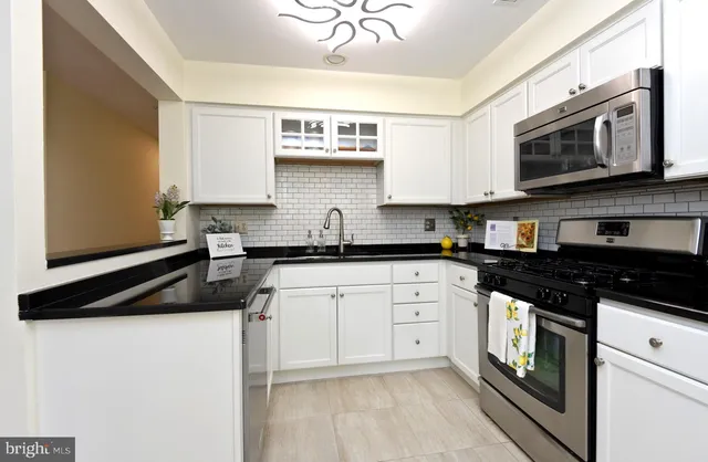 a kitchen with granite countertop a sink a stove and cabinets