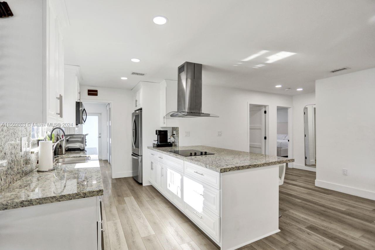 a large kitchen with stainless steel appliances granite countertop a sink stove and refrigerator