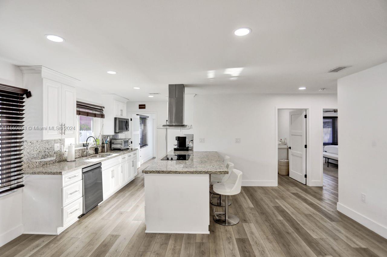 2800 Southwest 26th Street Miami, FL 33133 - Photo 67 of 72 a large kitchen with stainless steel appliances kitchen island granite countertop a stove a sink a refrigerator and white cabinets with wooden floor