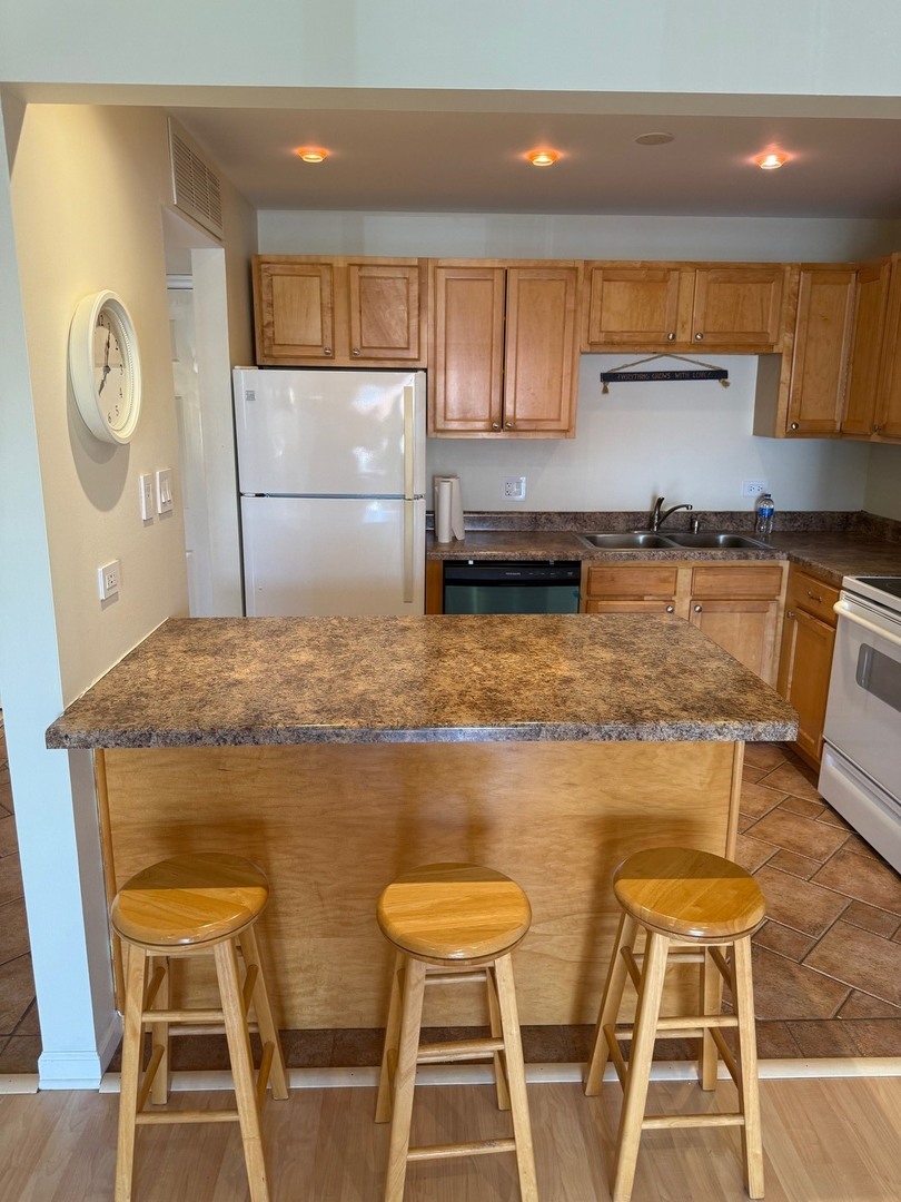 910 Beau Drive, Unit 211 Des Plaines, IL 60016 - Photo 5 of 11 a kitchen with stainless steel appliances granite countertop a sink a stove a dining table and chairs