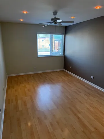 an empty room with wooden floor windows and ceiling fan